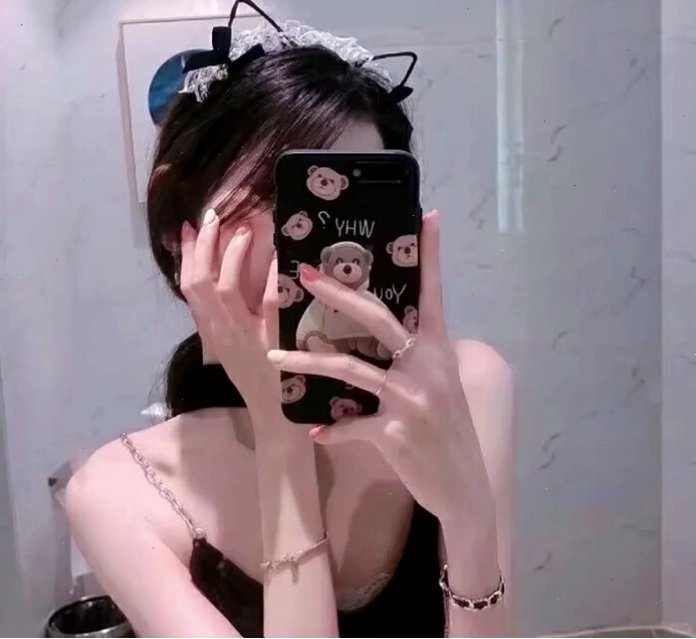 Cô gái che mặt bằng điện thoại khi nhìn vào gương