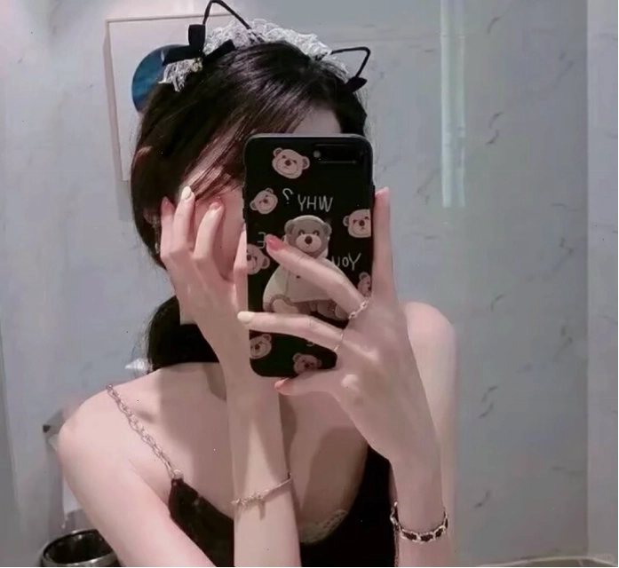 Cô gái trẻ nhìn vào gương, dùng điện thoại che mặt